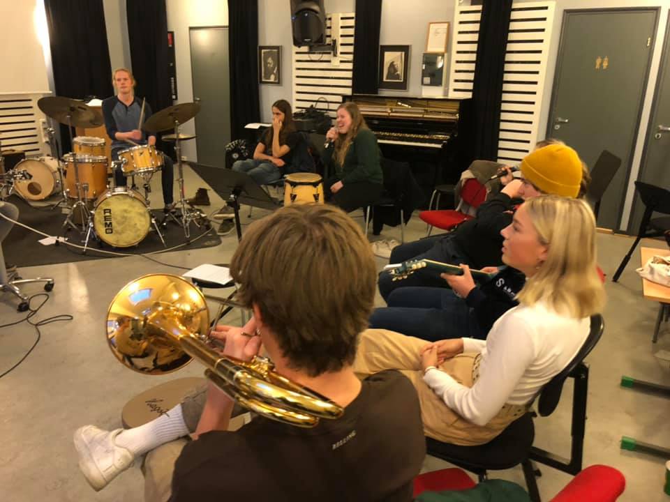 Elever fra jazzlinja sittende i ring, spiller